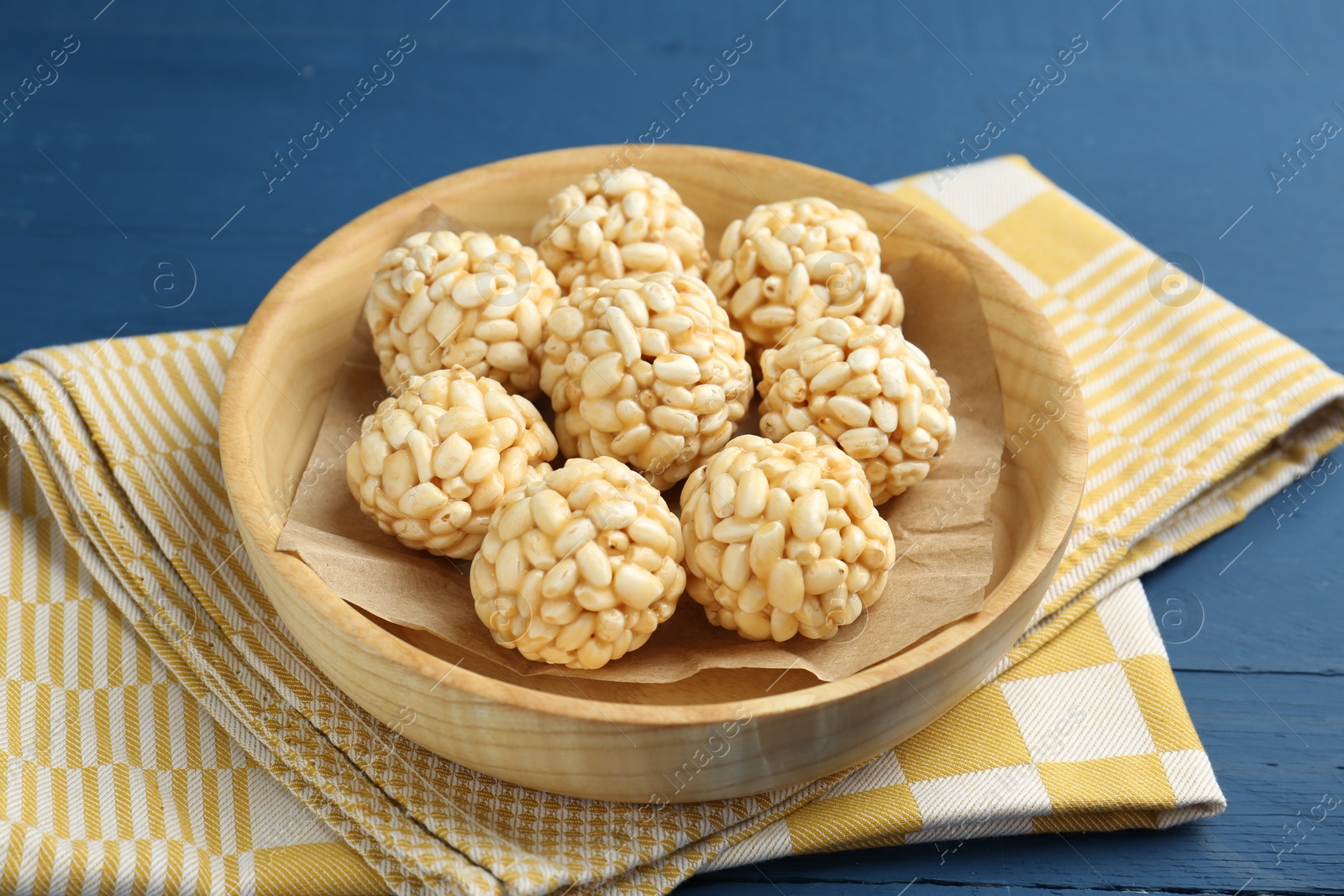 Photo of Tasty puffed rice balls on blue wooden table, closeup