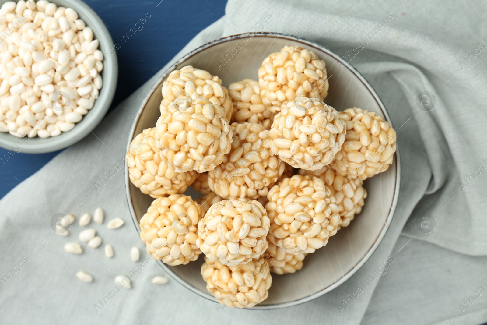 Photo of Tasty puffed rice balls and grains on blue table, top view