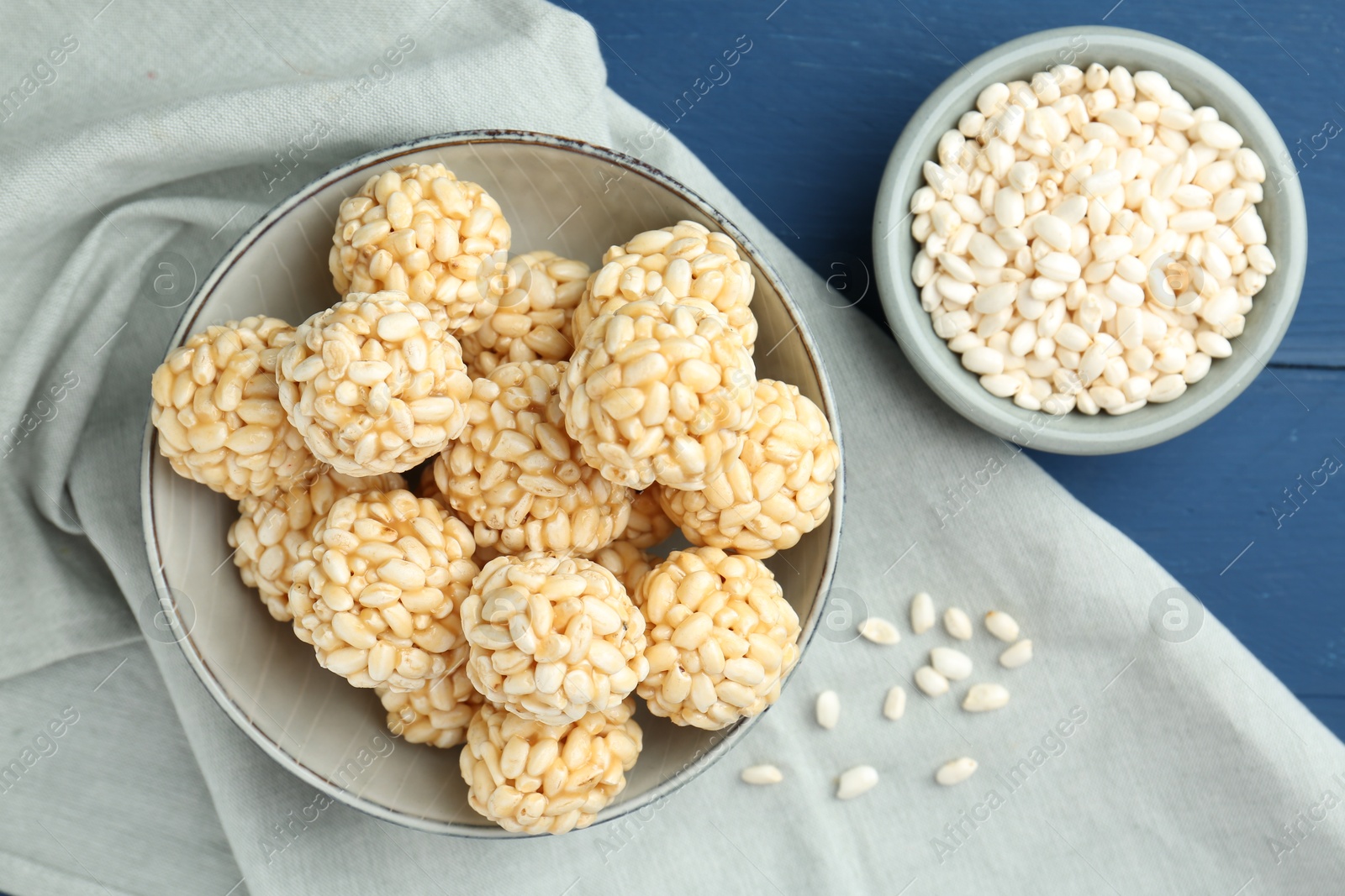 Photo of Tasty puffed rice balls and grains on blue wooden table, top view