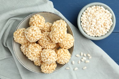 Photo of Tasty puffed rice balls and grains on blue wooden table, top view