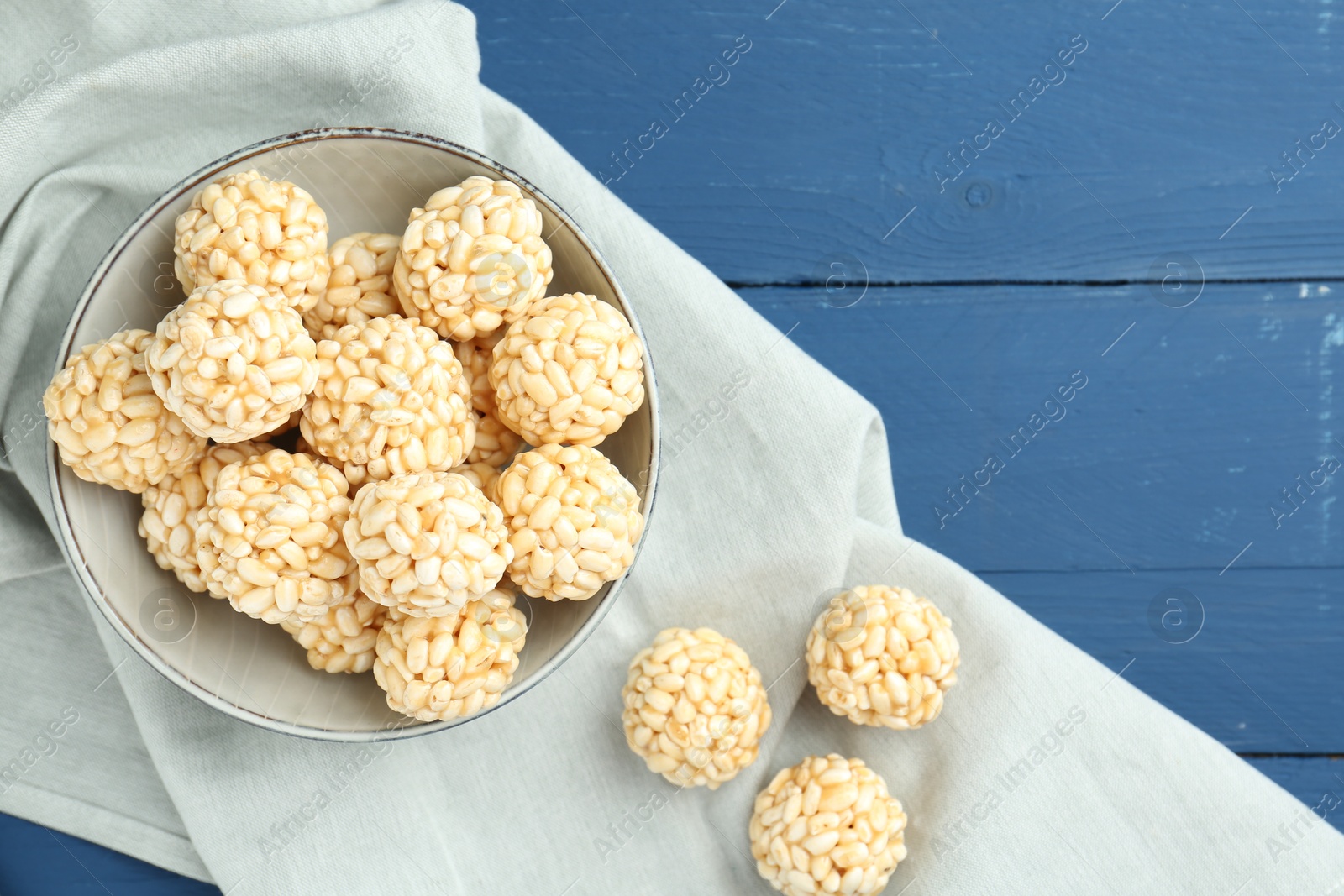 Photo of Tasty puffed rice balls on blue wooden table, top view. Space for text