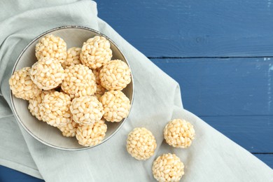 Photo of Tasty puffed rice balls on blue wooden table, top view. Space for text