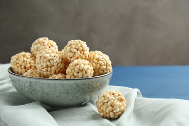 Photo of Tasty puffed rice balls in bowl on blue table, closeup. Space for text