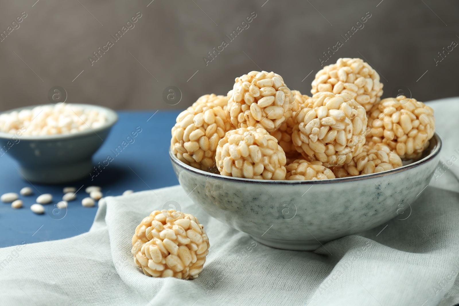 Photo of Tasty puffed rice balls in bowl on blue table, closeup