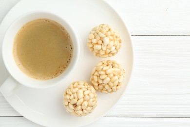 Photo of Tasty puffed rice balls and coffee on white wooden table, top view. Space for text