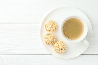 Tasty puffed rice balls and coffee on white wooden table, top view. Space for text