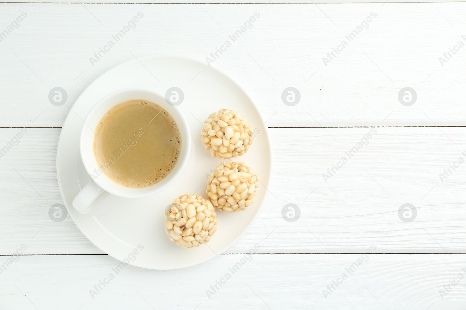 Photo of Tasty puffed rice balls and coffee on white wooden table, top view. Space for text