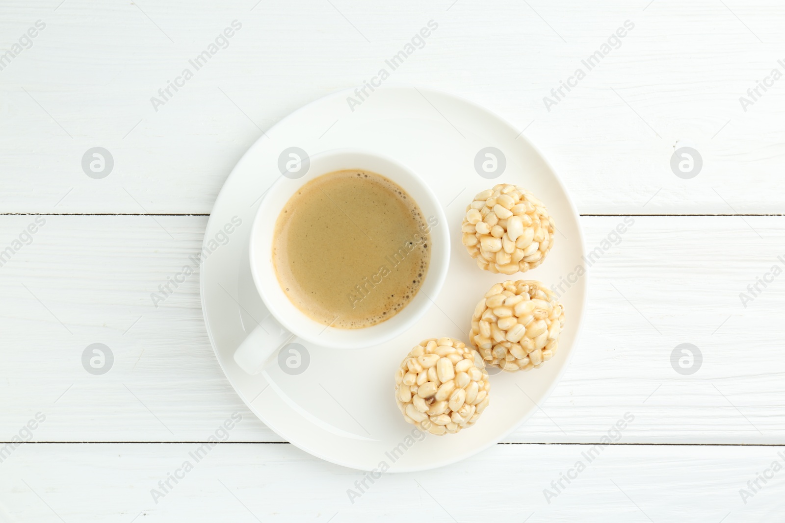 Photo of Tasty puffed rice balls and coffee on white wooden table, top view