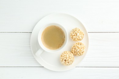 Tasty puffed rice balls and coffee on white wooden table, top view