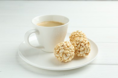 Photo of Tasty puffed rice balls and coffee on white wooden table, closeup