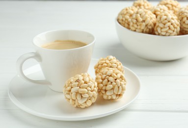 Photo of Tasty puffed rice balls and coffee on white wooden table, closeup