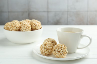 Photo of Tasty puffed rice balls and coffee on white wooden table, closeup