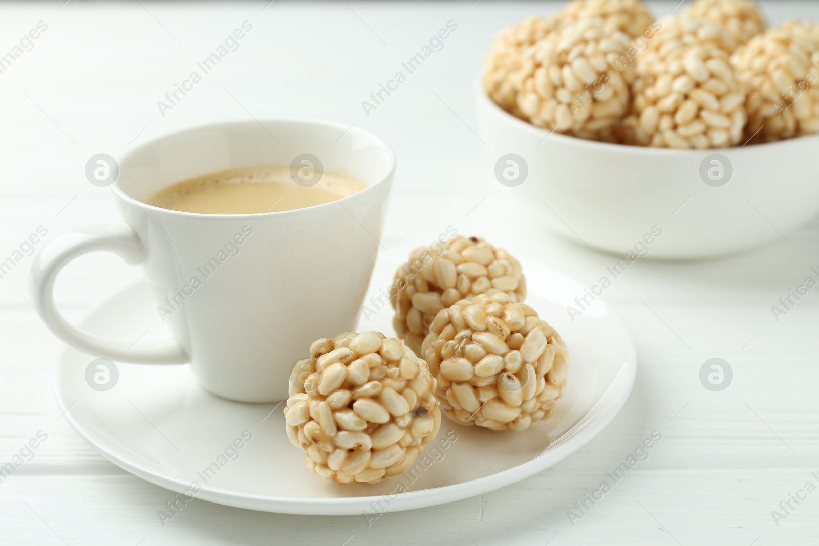 Photo of Tasty puffed rice balls and coffee on white wooden table, closeup