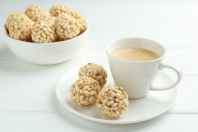 Tasty puffed rice balls and coffee on white wooden table, closeup