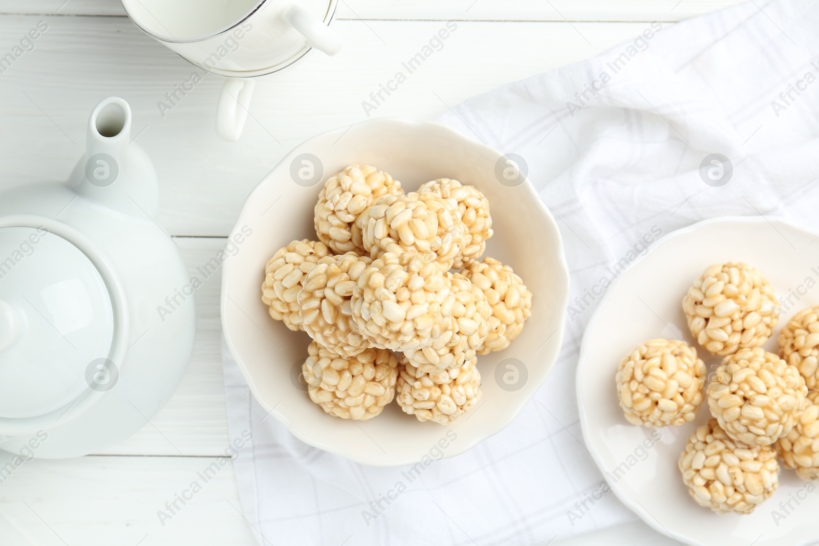 Photo of Tasty puffed rice balls served on white wooden table, flat lay