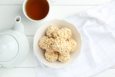 Photo of Tasty puffed rice balls and tea on white wooden table, flat lay