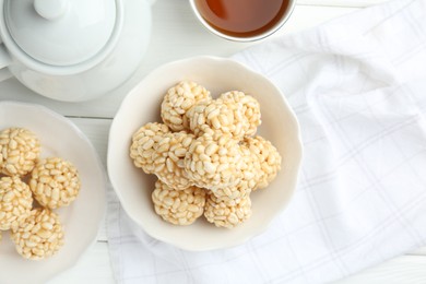 Photo of Tasty puffed rice balls and tea on white wooden table, flat lay