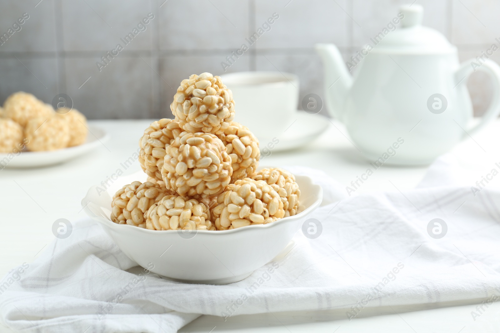 Photo of Tasty puffed rice balls in bowl on white table