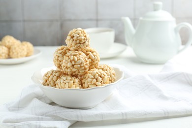 Photo of Tasty puffed rice balls in bowl on white table