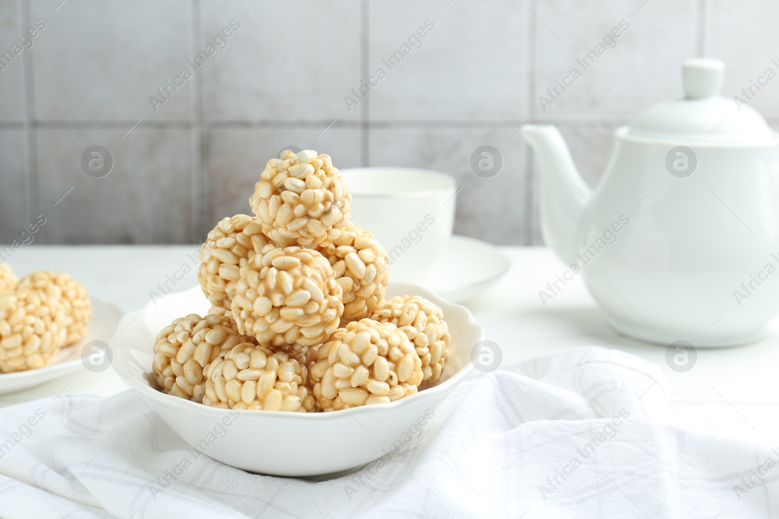 Photo of Tasty puffed rice balls in bowl on white table