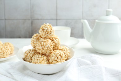 Photo of Tasty puffed rice balls in bowl on white table