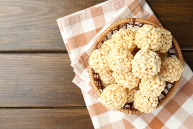 Photo of Tasty puffed rice balls in wicker basket on wooden table, top view. Space for text