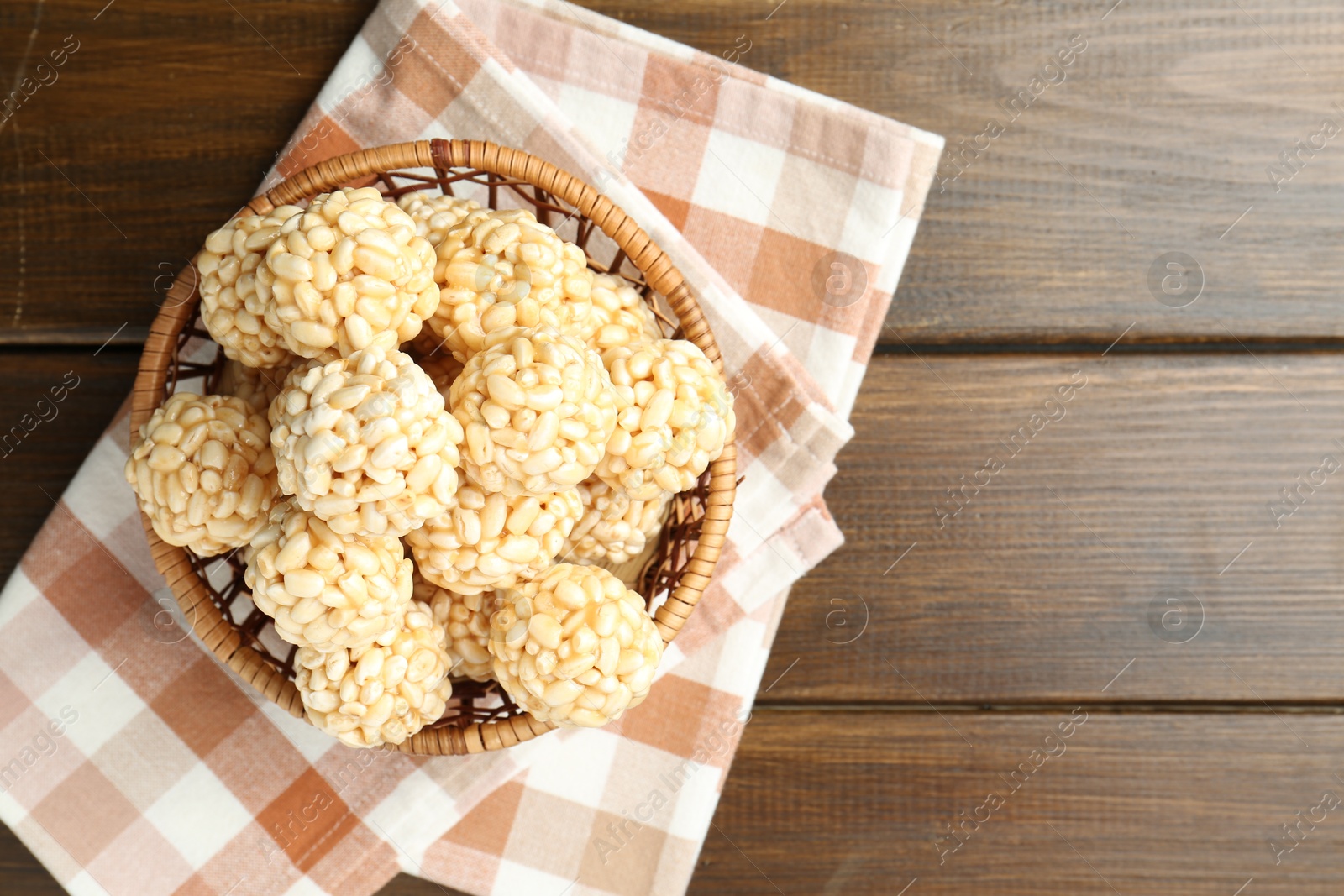 Photo of Tasty puffed rice balls in wicker basket on wooden table, top view. Space for text