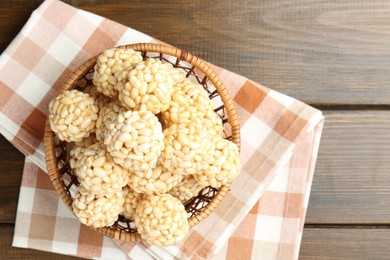 Photo of Tasty puffed rice balls in wicker basket on wooden table, top view. Space for text