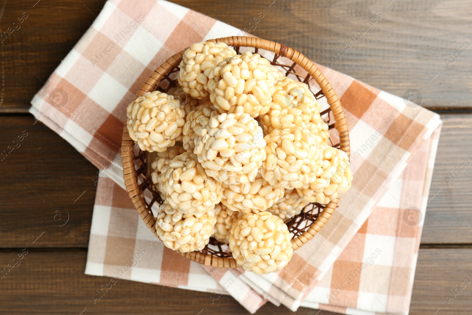 Photo of Tasty puffed rice balls in wicker basket on wooden table, top view