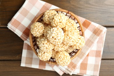 Tasty puffed rice balls in wicker basket on wooden table, top view