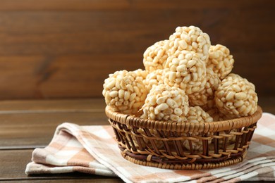 Photo of Tasty puffed rice balls in wicker basket on wooden table, space for text