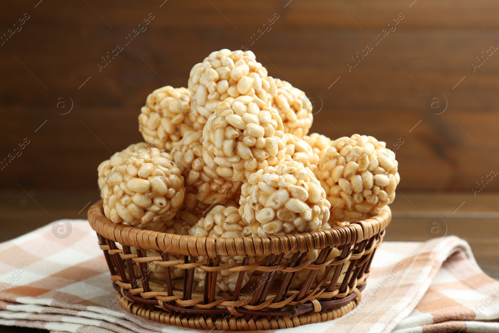 Photo of Tasty puffed rice balls in wicker basket on table, closeup