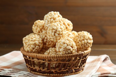 Tasty puffed rice balls in wicker basket on table, closeup