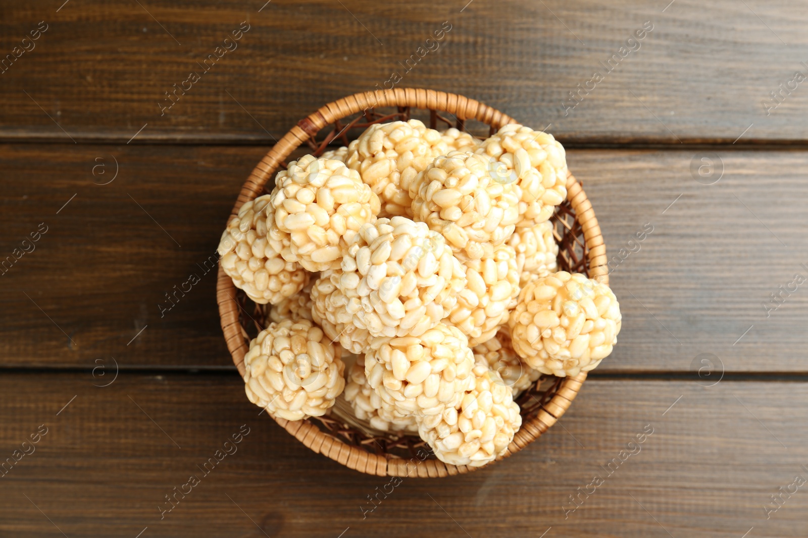 Photo of Tasty puffed rice balls in wicker basket on wooden table, top view