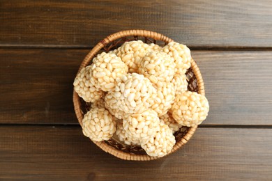 Tasty puffed rice balls in wicker basket on wooden table, top view