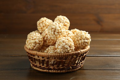 Photo of Tasty puffed rice balls in wicker basket on wooden table, closeup