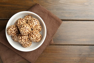 Photo of Tasty chocolate puffed rice balls in bowl on wooden table, top view. Space for text