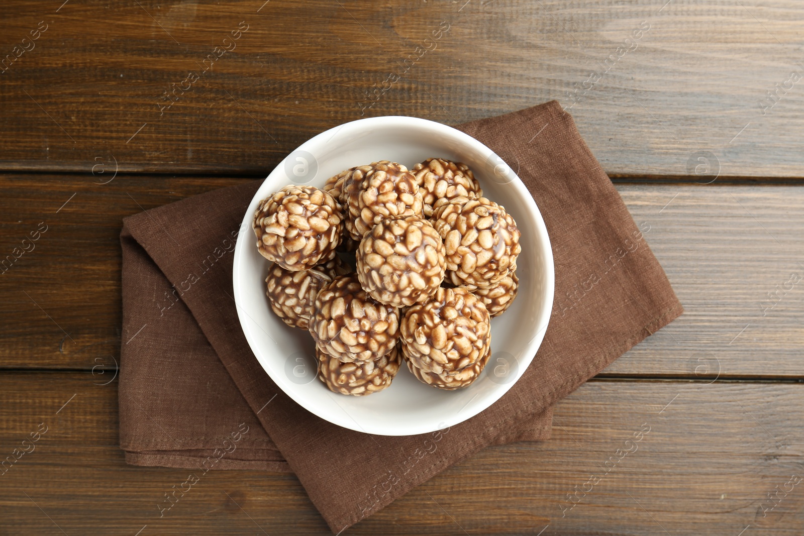 Photo of Tasty chocolate puffed rice balls in bowl on wooden table, top view