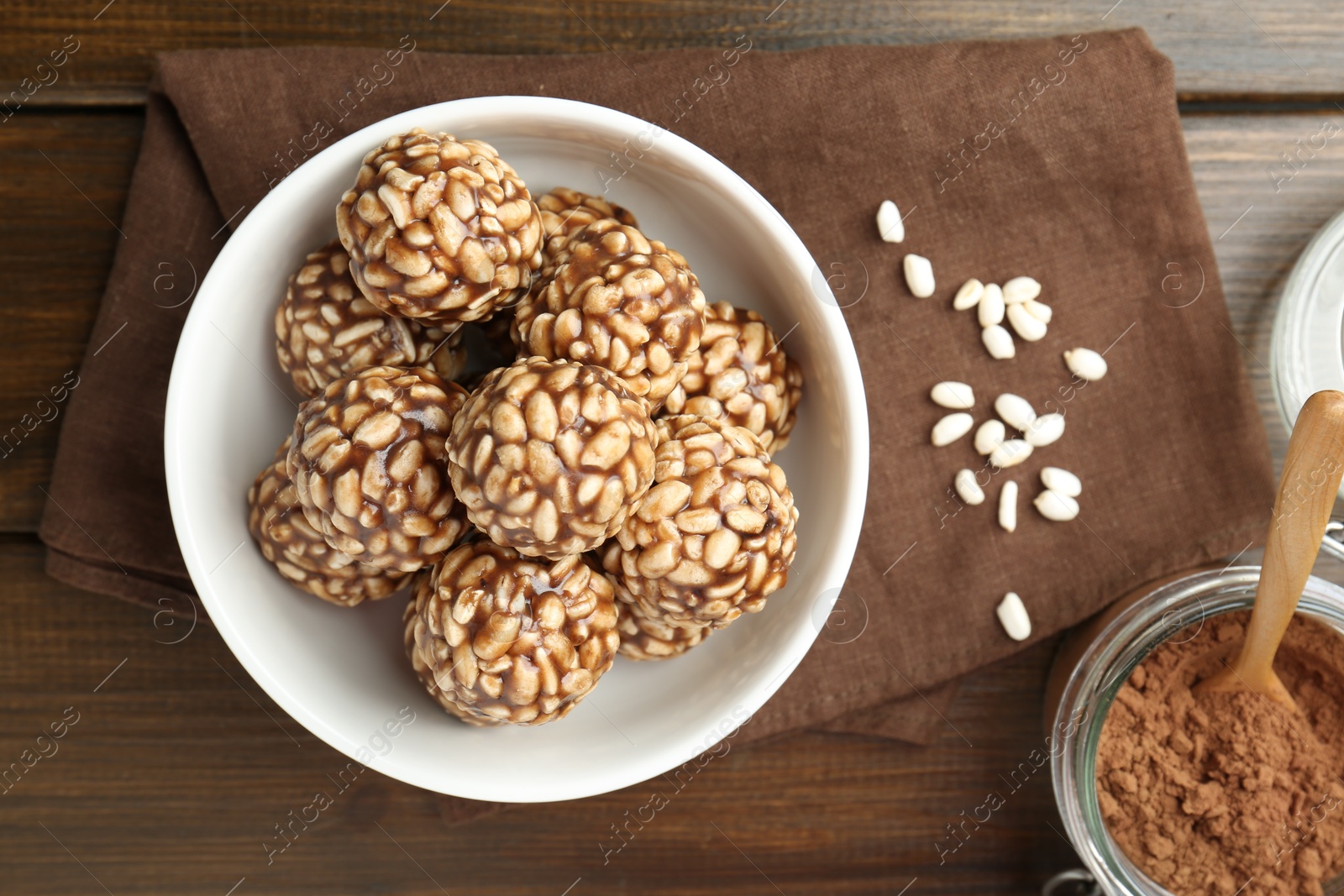 Photo of Tasty chocolate puffed rice balls and cocoa powder on wooden table, top view