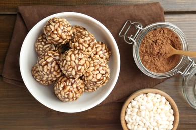 Tasty chocolate puffed rice balls and ingredients on wooden table, flat lay