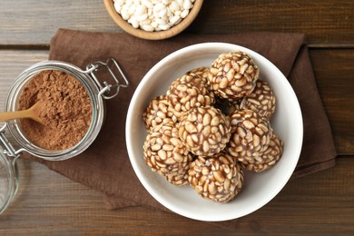 Tasty chocolate puffed rice balls and ingredients on wooden table, flat lay