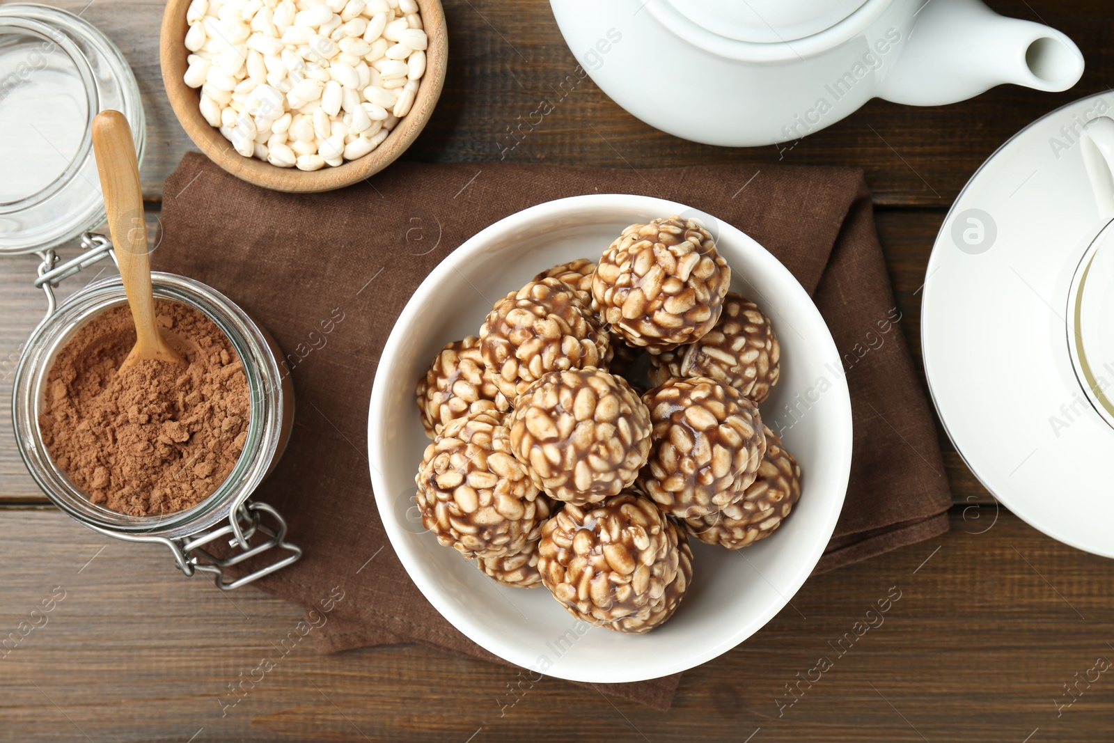 Photo of Tasty chocolate puffed rice balls served on wooden table, flat lay