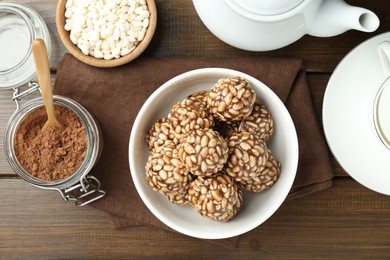 Photo of Tasty chocolate puffed rice balls served on wooden table, flat lay