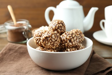 Photo of Tasty chocolate puffed rice balls in bowl on table, closeup