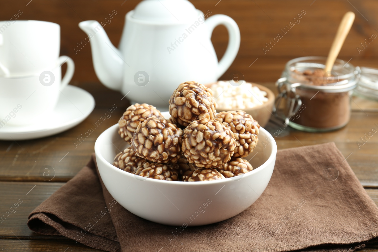 Photo of Tasty chocolate puffed rice balls served on wooden table, closeup