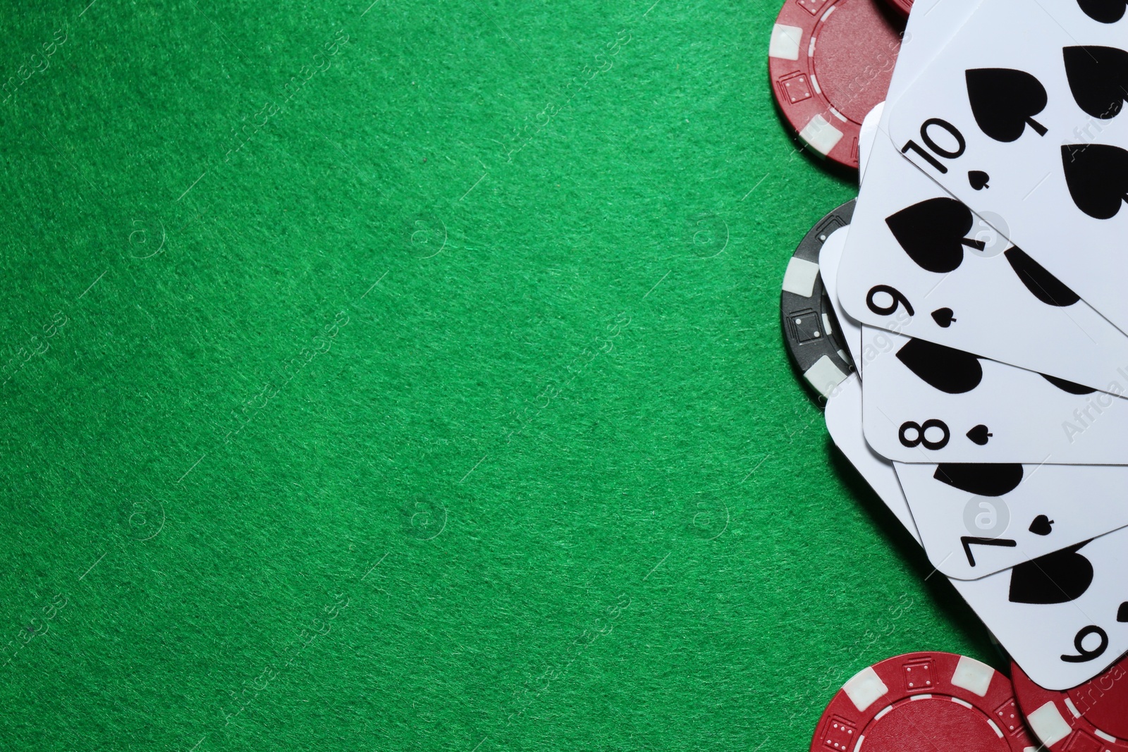 Photo of Poker chips and playing cards on green table, flat lay. Space for text