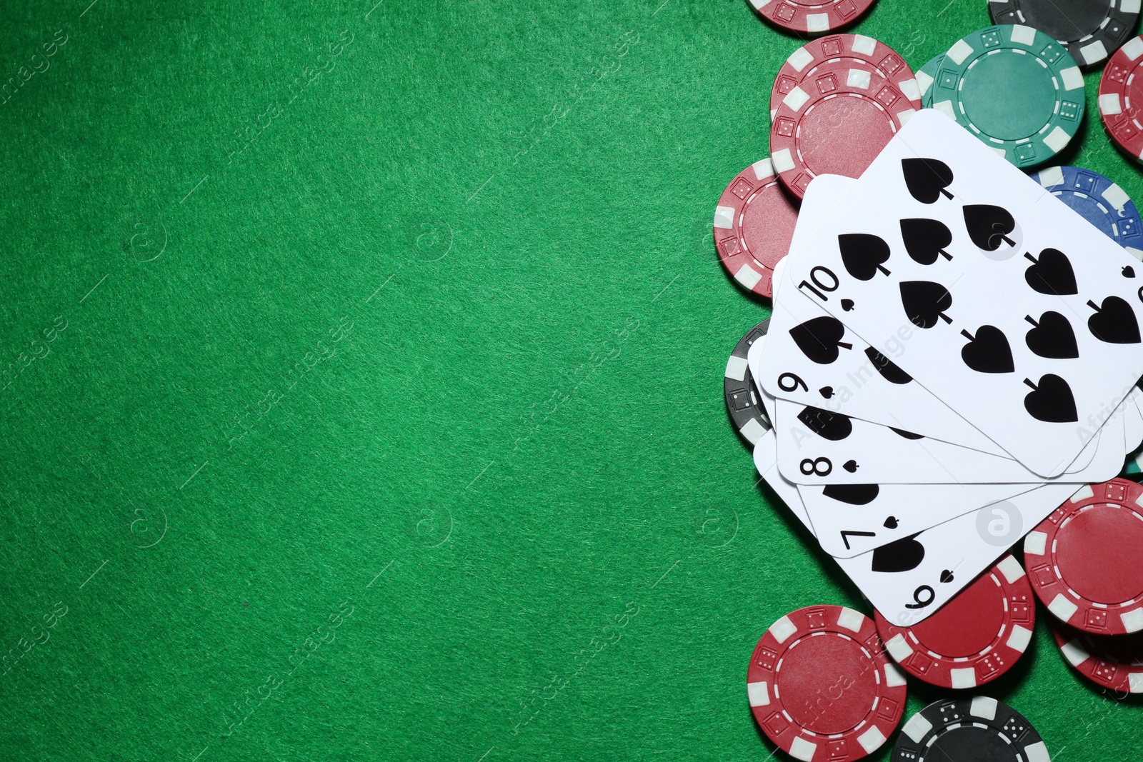 Photo of Poker chips and playing cards on green table, flat lay. Space for text