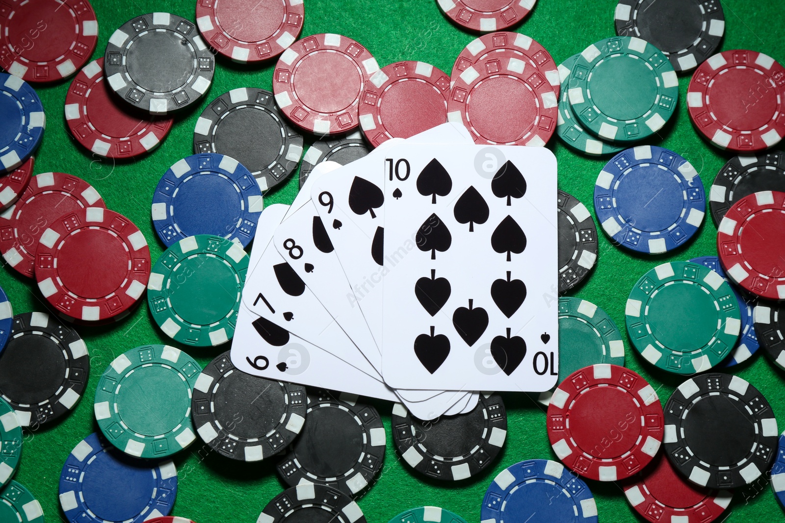 Photo of Poker chips and playing cards on green table, flat lay