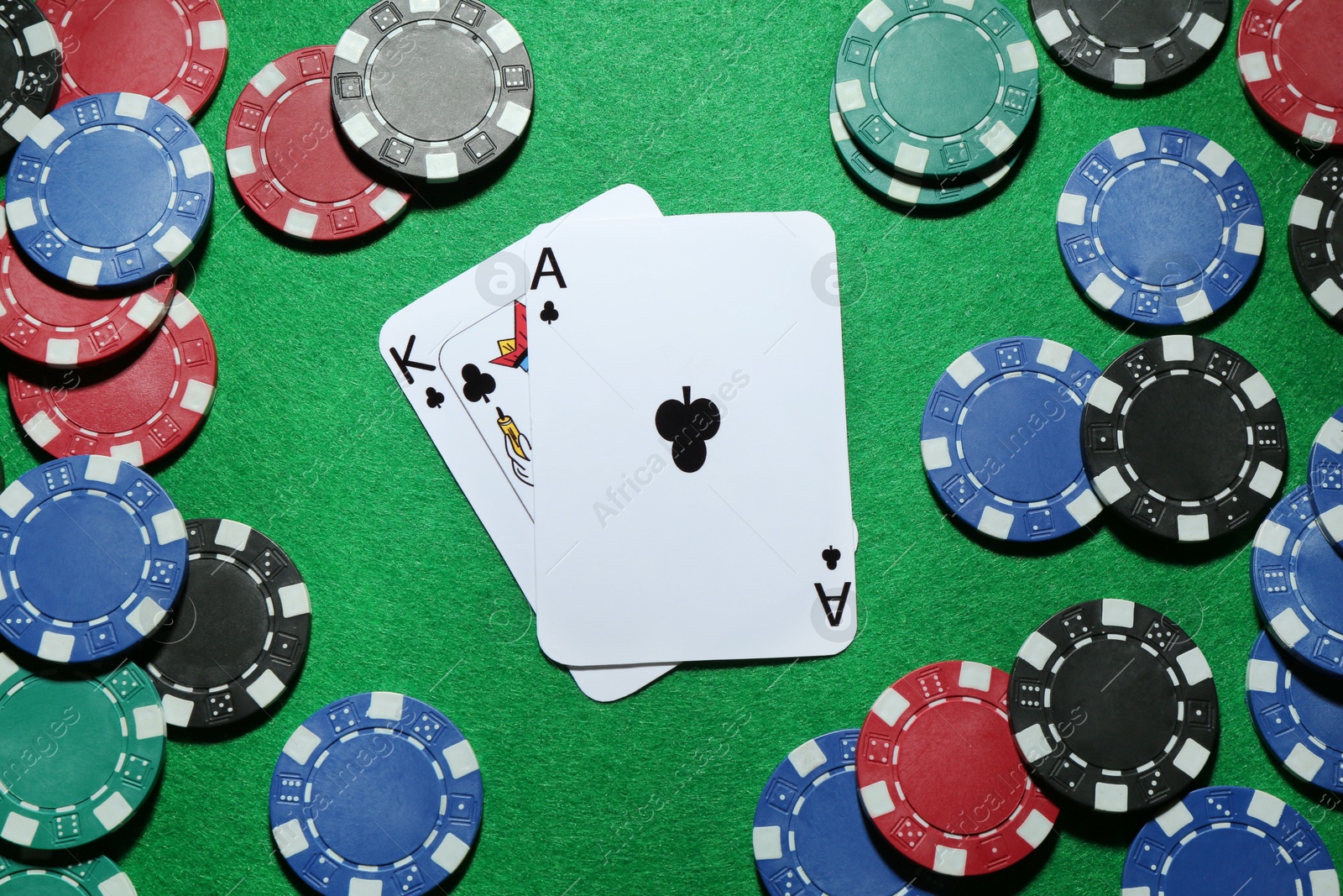 Photo of Poker chips and playing cards on green table, flat lay