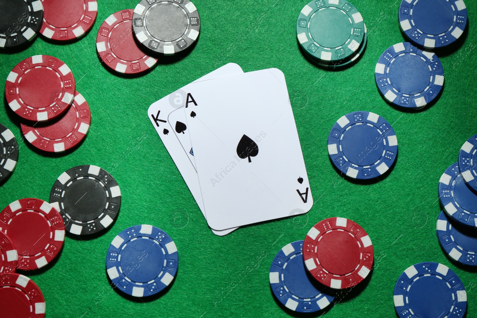 Photo of Poker chips and playing cards on green table, flat lay